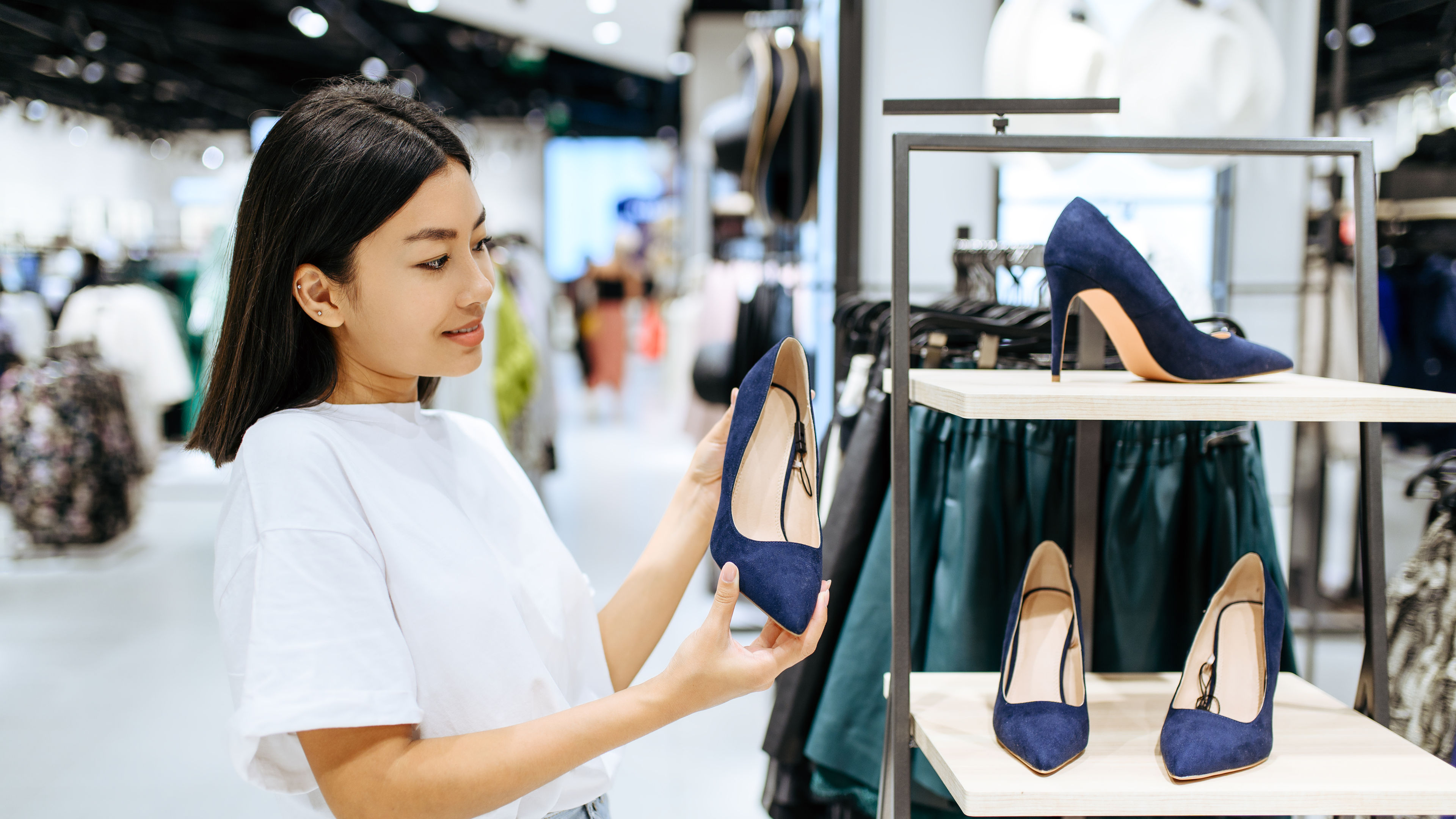 Woman shopping for navy blue high heels in a fashion retail store.