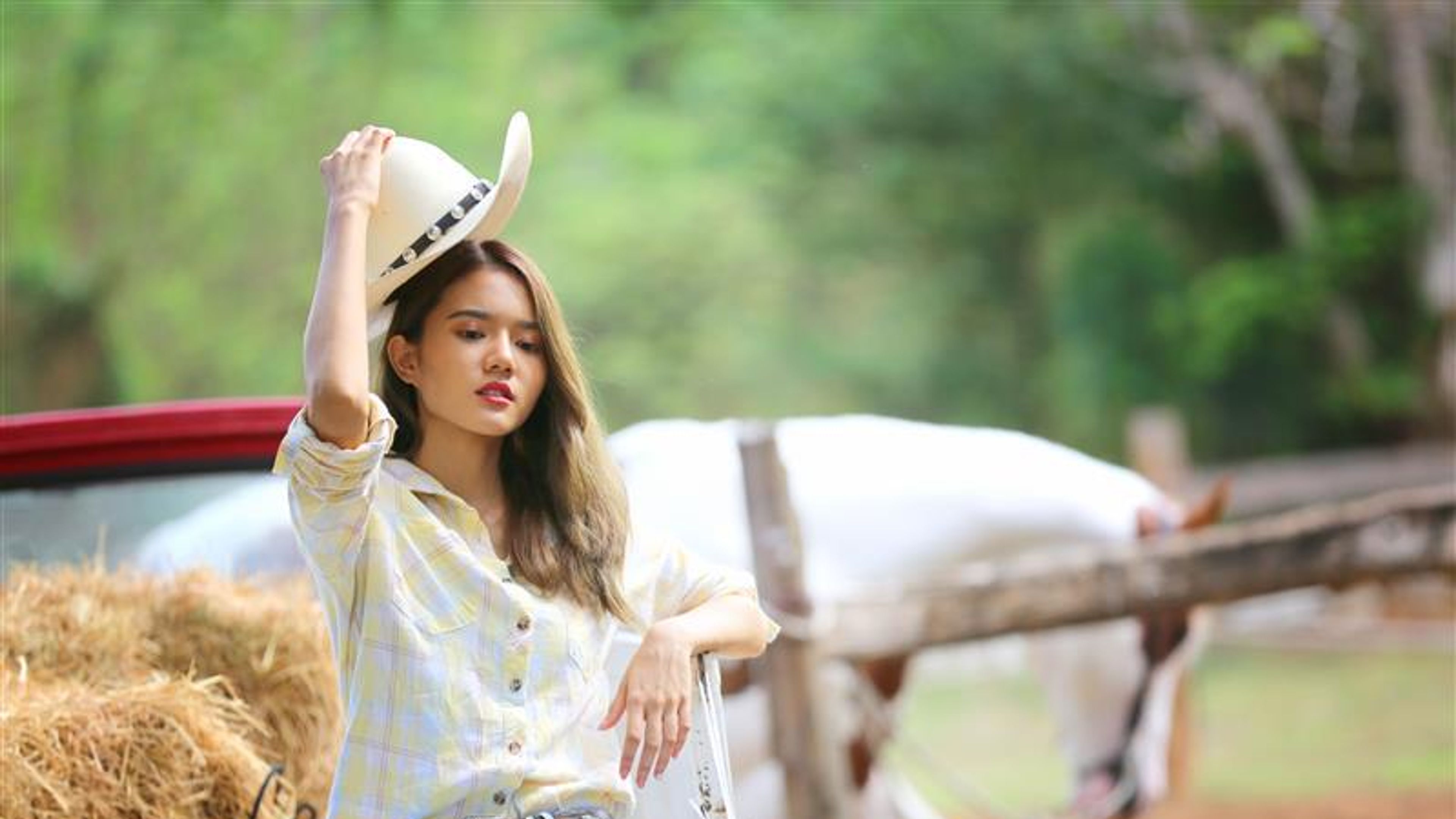 Isang blonde na buhok babae sa isang cowgirl outfit nakatayo na may isang kabayo sa isang baka sakahan