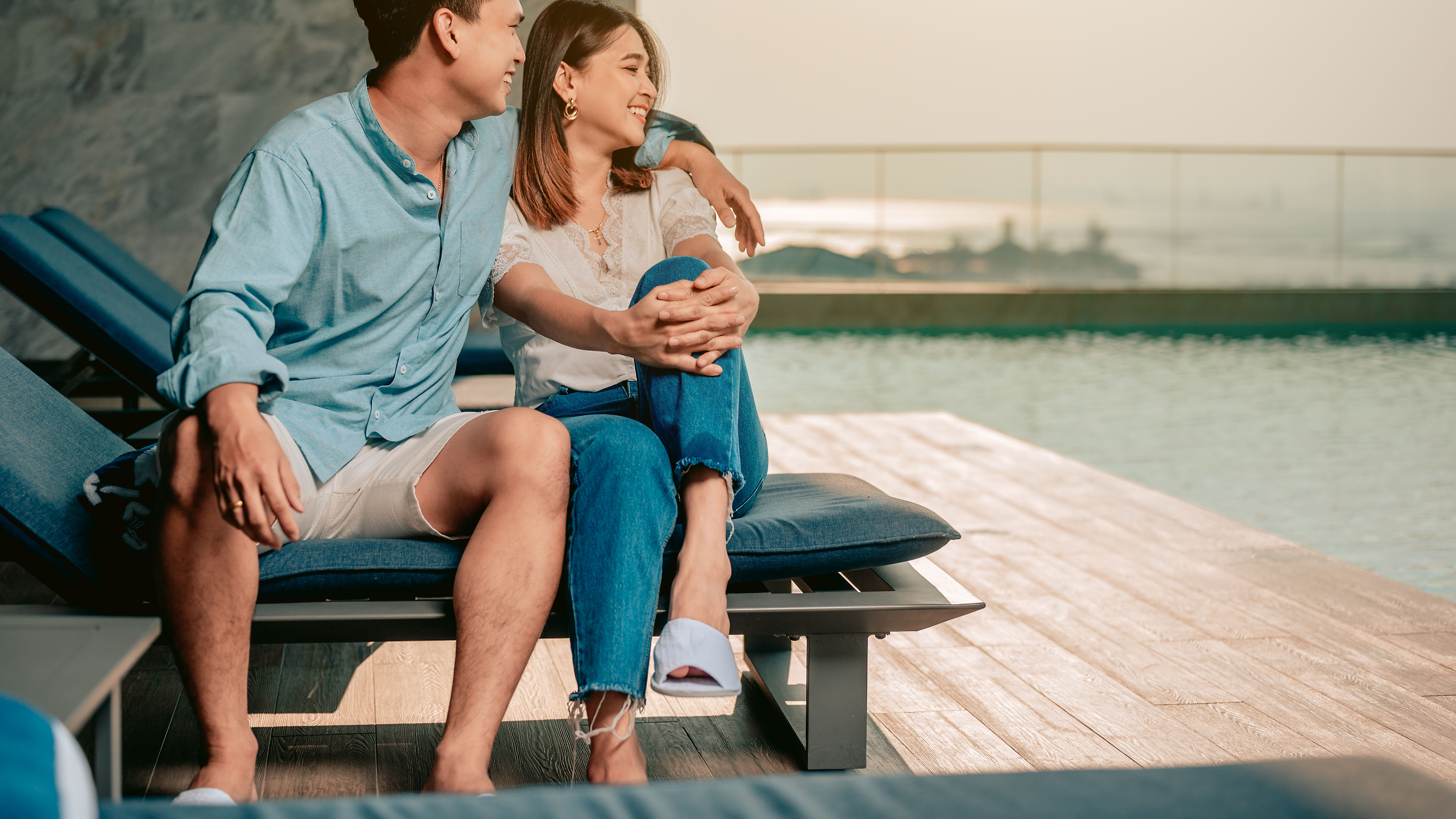 A couple sitting by a pool at sunset