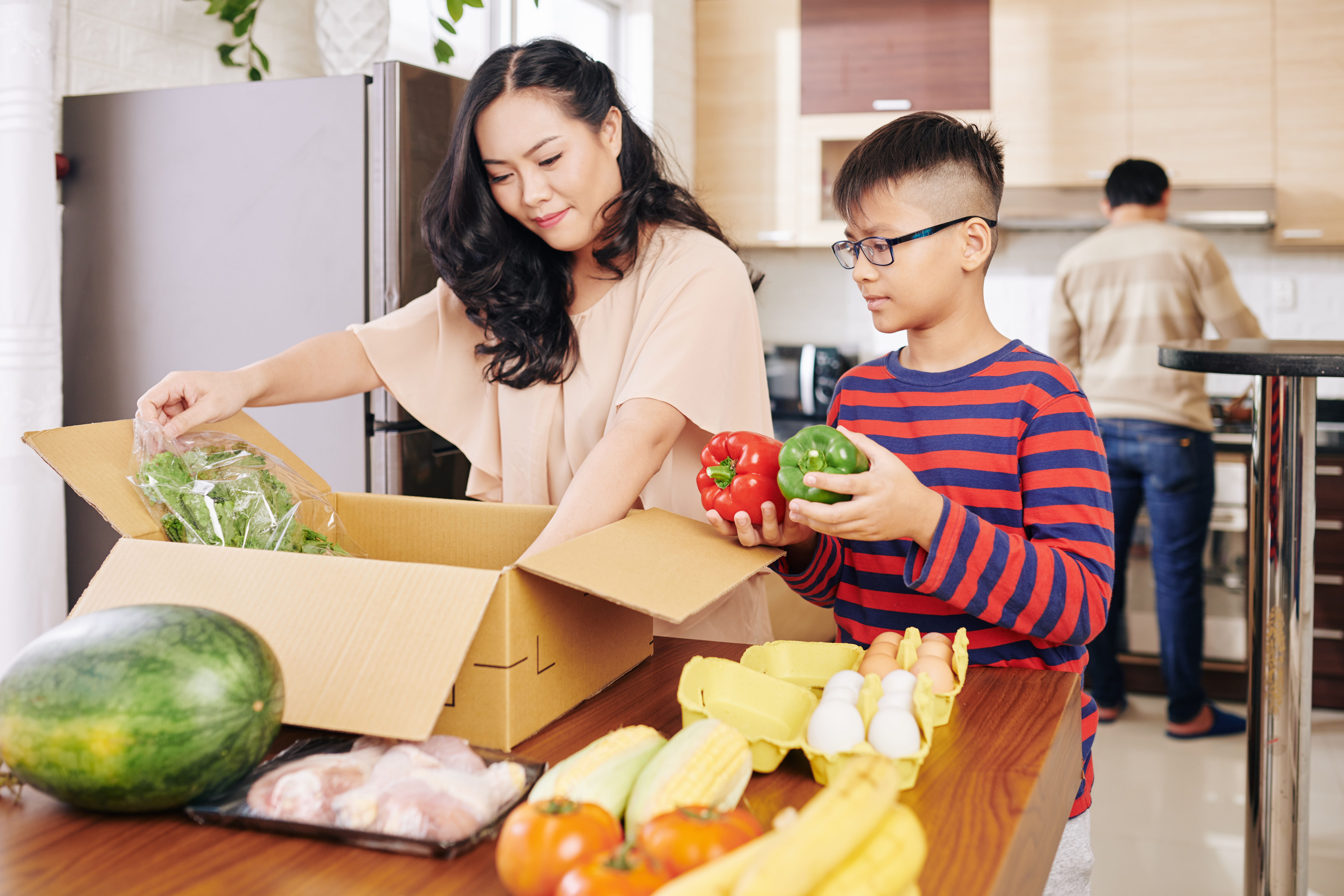 A mother and a son unboxing groceries. 