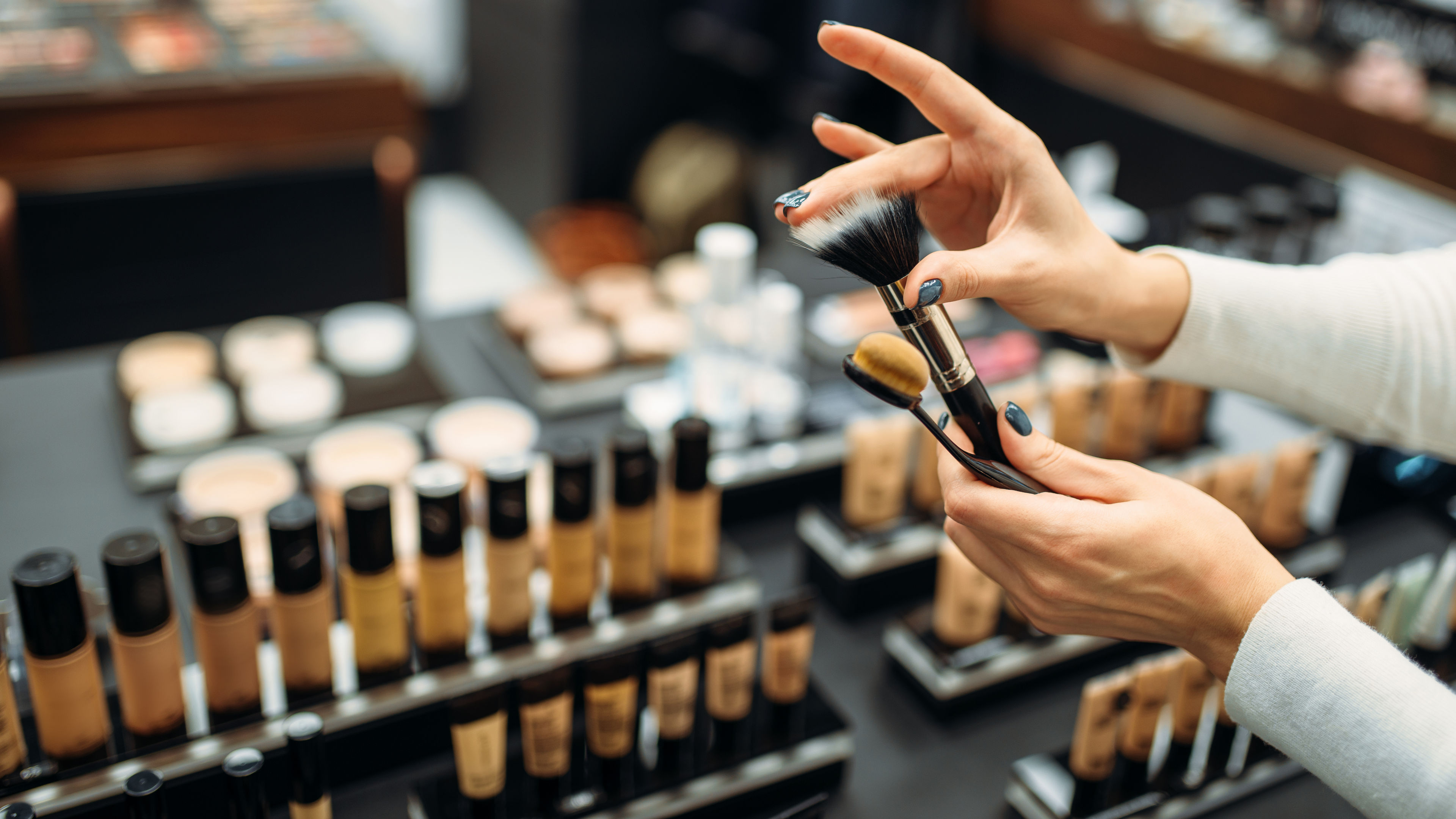 Female customer choosing brushes in makeup shop