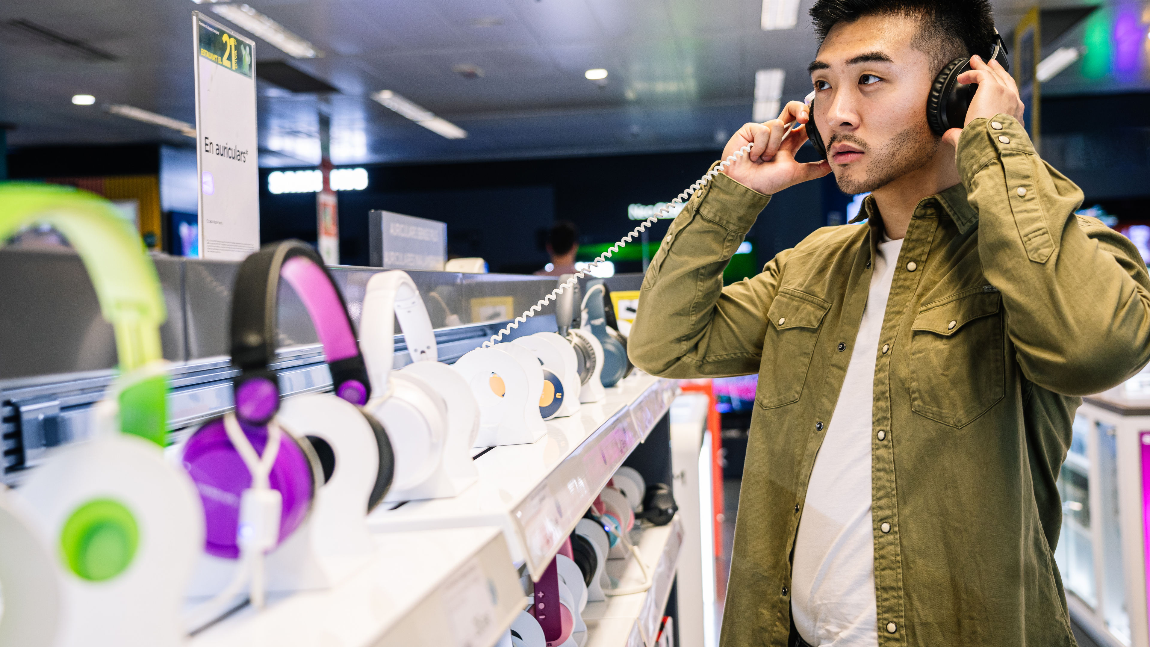 Man Sampling Headphones in Tech Store 

 