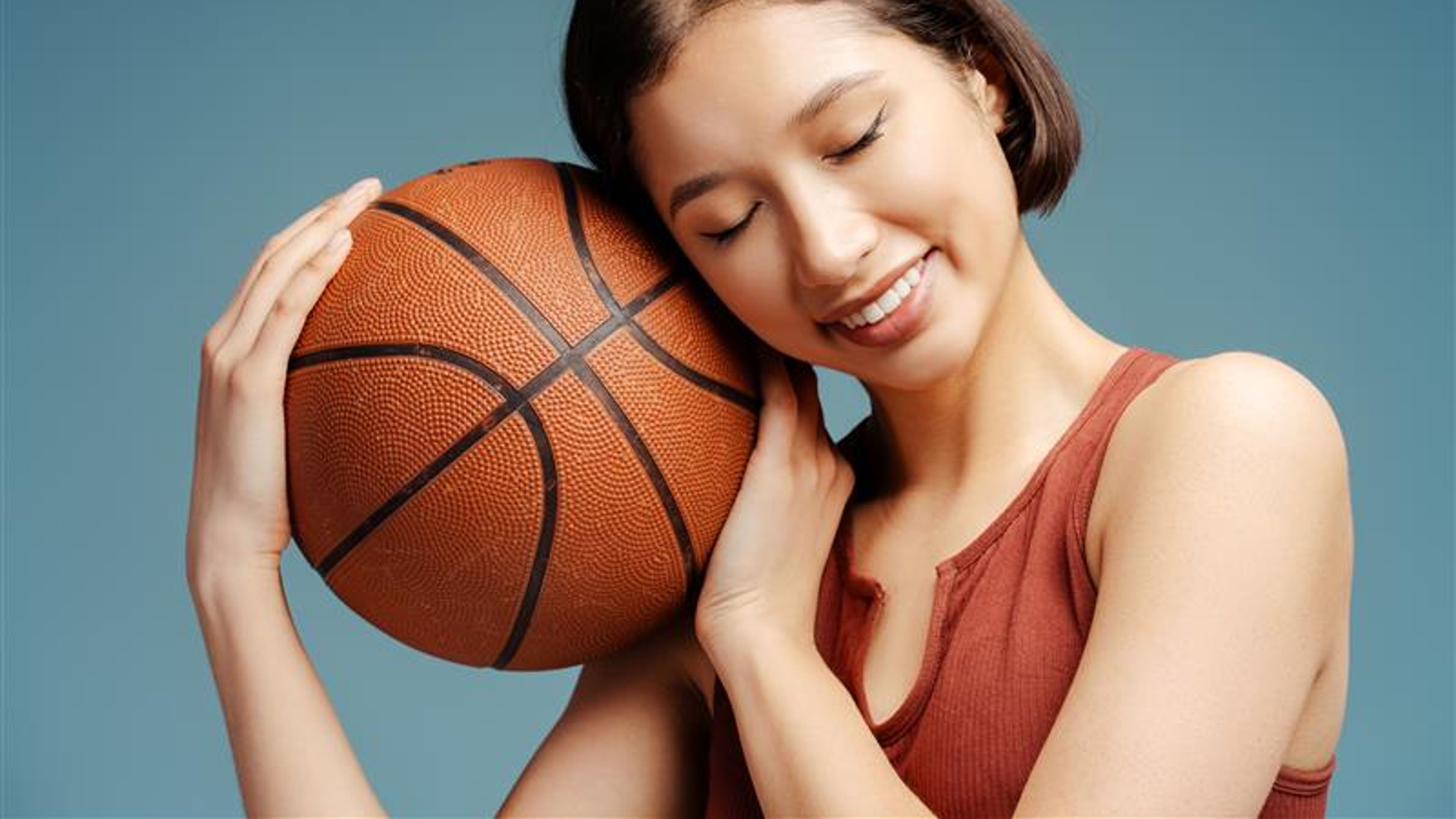 Smiling woman holding ball with closed eyes posing for pictures isolated