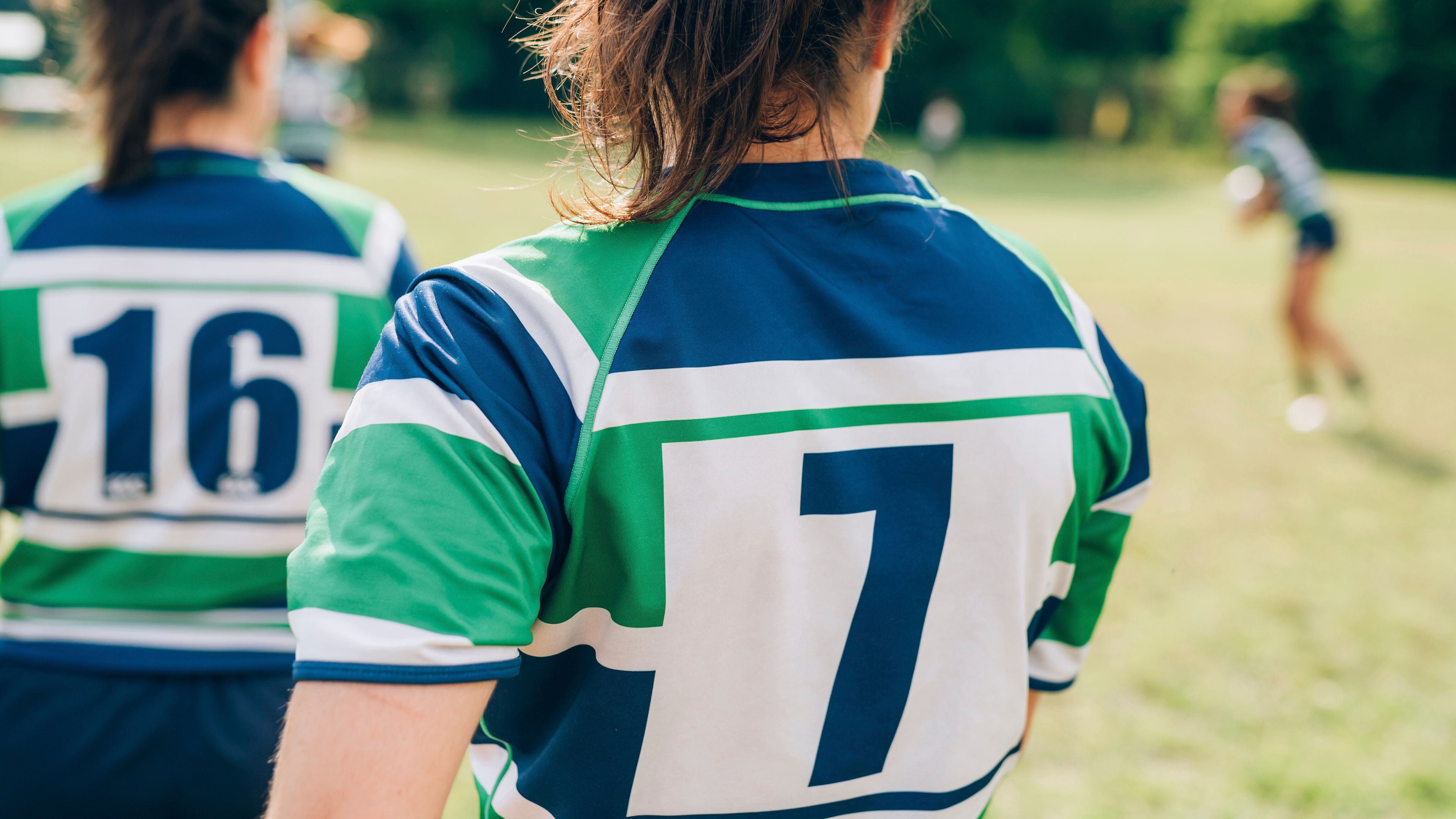 Dalawang kababaihan na nakasuot ng berde at asul na rugby jersey