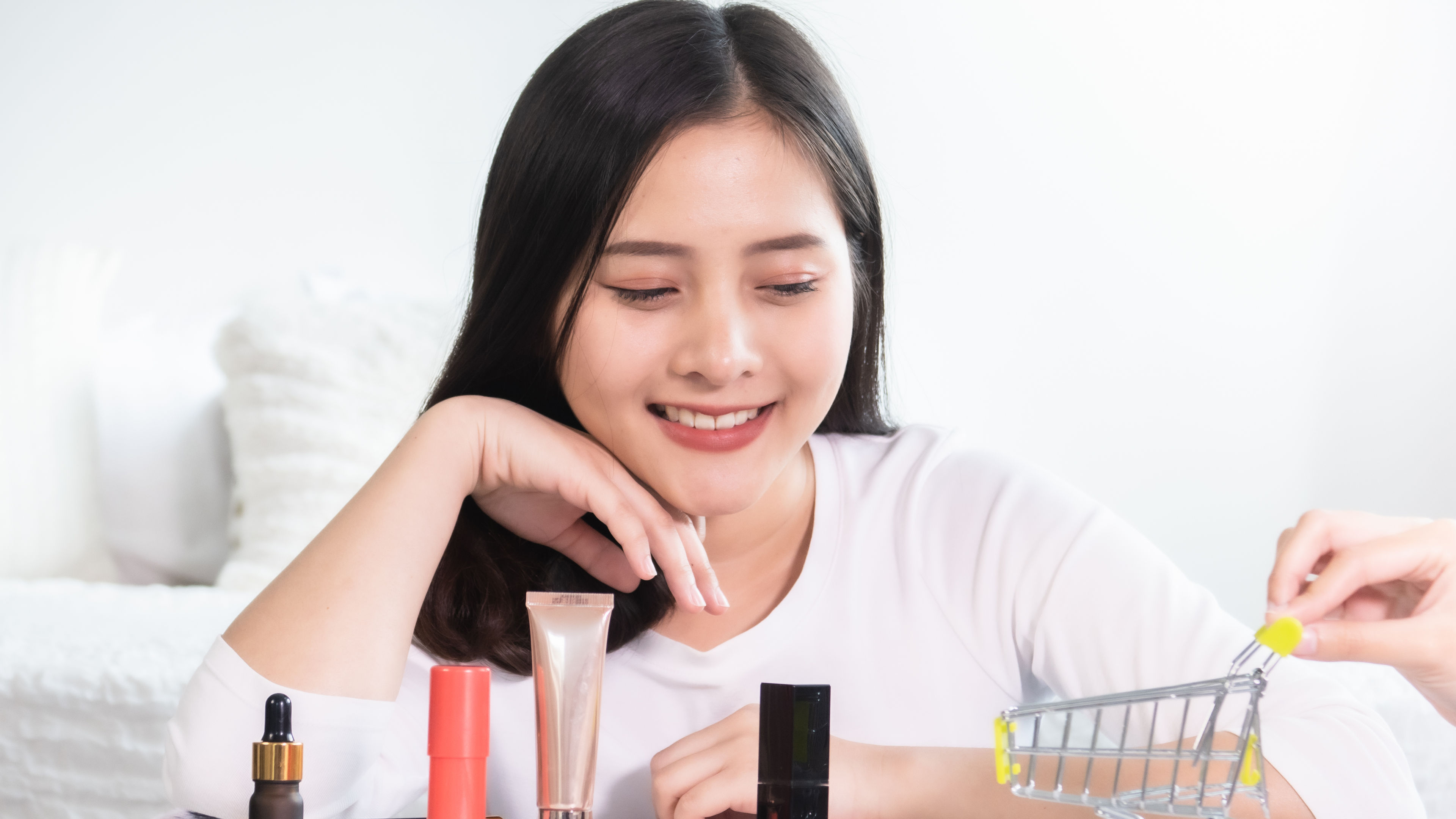 Woman smiling at beauty products with a mini shopping cart 
